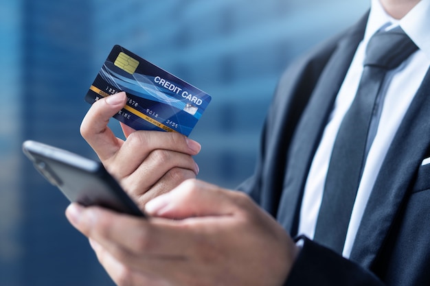 De zakenman betaalt of winkelt door creditcard met smartphone