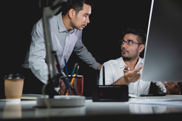 De zakenmanmedewerkers die van Aasian werk bespreken bij nacht