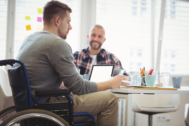 De zakenmanzitting van de handicap met collega in bureau