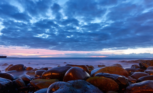 De zee na zonsondergang en het strand met grote stenen. landschap, schemering zeegezicht. tenerife, de canarische eilanden