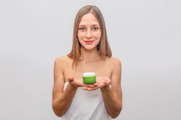 De zekere en vrolijke jonge vrouw bevindt zich en houdt glas room met beide handen. Ze ziet er recht uit. Blonde jonge vrouw ziet er mooi uit.