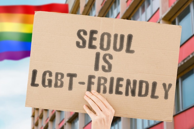 De zin "Seoul is LGBT-Friendly" op een spandoek in de hand van een man met een wazige LGBT-vlag op de achtergrond. Menselijke relaties. verschillend. Verschillend. vrijheid. Seksualiteit. Maatschappelijke kwesties. Samenleving