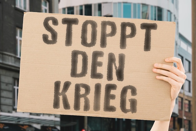 De zin stop de oorlog staat op een spandoek in mannenhanden met wazige achtergrond troepen vijandigheid agressie vechten aanval verdediging overleven hoop hulp hulp slachtoffers vluchtelingen