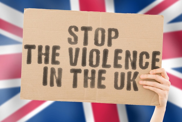 De zin Stop het geweld in het VK staat op een spandoek in mannenhanden met een vage Britse vlag op de achtergrond Trieste rechten Veiligheid Sociale stress Bestrijding Haat Wreedheid Woedend