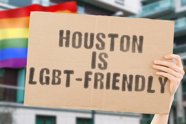 De zinsnede "Houston is LGBT-Friendly" op een spandoek in de hand van mannen met een wazige LGBT-vlag op de achtergrond. Menselijke relaties. verschillend. Verschillend. vrijheid. Seksualiteit. Maatschappelijke kwesties. Samenleving