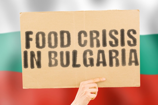 De zinsnede Voedselcrisis in Bulgarije staat op een spandoek in mannenhanden met een wazige Bulgaarse vlag op de achtergrond Crisis Finance Life Nutrition Bread Ramp Collapse Sociale kwestie