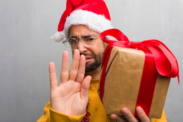 De zitting van de jonge mens met giften die Kerstmis vieren die voorzijde indienen