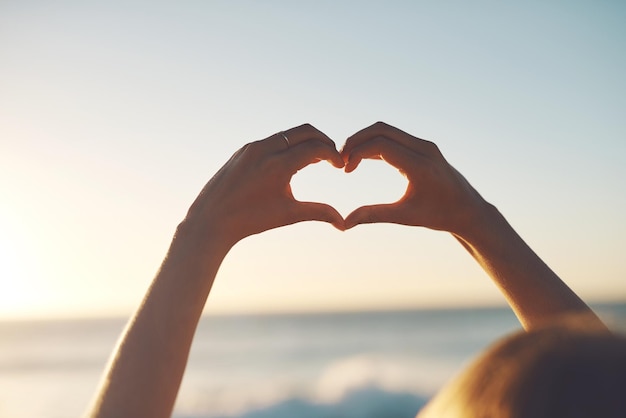 De zomer is de beste tijd van het jaar Bijgesneden opname van een vrouw die een hartvorm maakt met haar handen