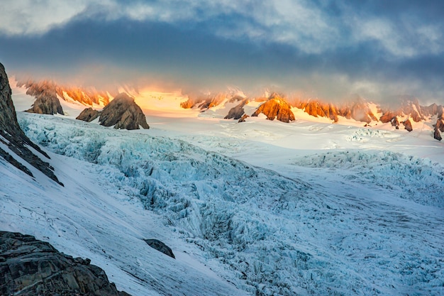 De zon barst door de dikke wolk op de top van de gletsjer in de toppen van de Zuidelijke Alpen
