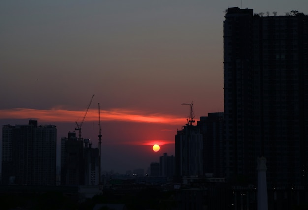 De zon die onder de wolkenkrabber en bouwgebouwen plaatst van Bangkok, Thailand