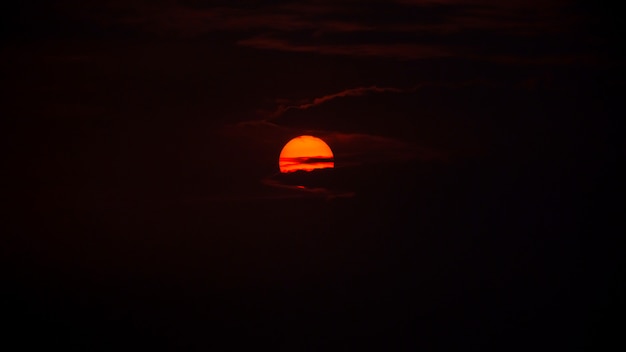 Foto de zon komt in de vroege ochtend achter de wolken op, de foto heeft wat geluid en graan.