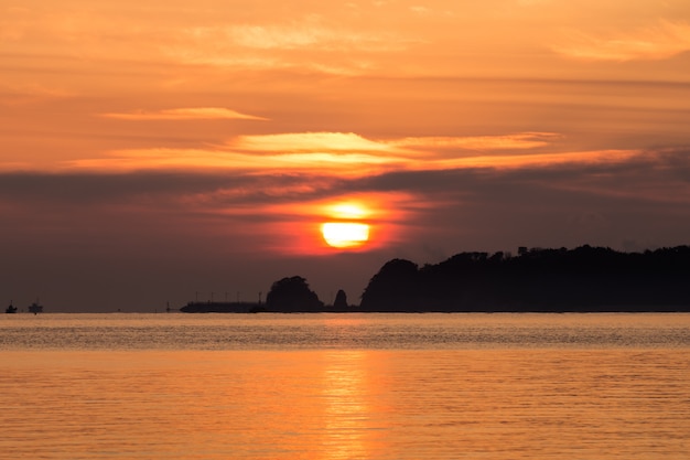 De zon komt op tussen het eiland en de wolken