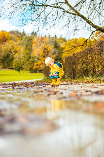 De zon schijnt altijd na de regen kleine band baby jongen draagt gele rubberen laarzen en geel