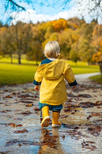 Foto de zon schijnt altijd na de regen kleine band baby jongen draagt gele rubberen laarzen en geel