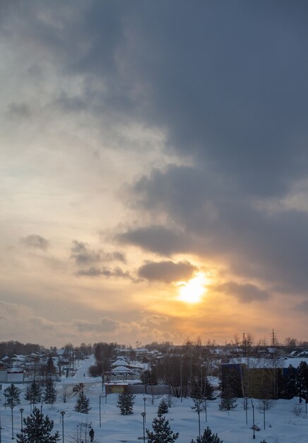 De zon tussen de wolken boven de winterstad.