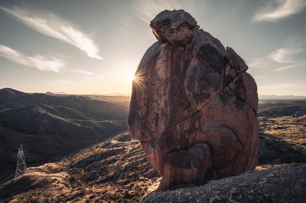 Foto de zonsopgang kijkt voorbij een enorme rots op een richel bij de ruïnes van sears kay in de sonora-woestijn.