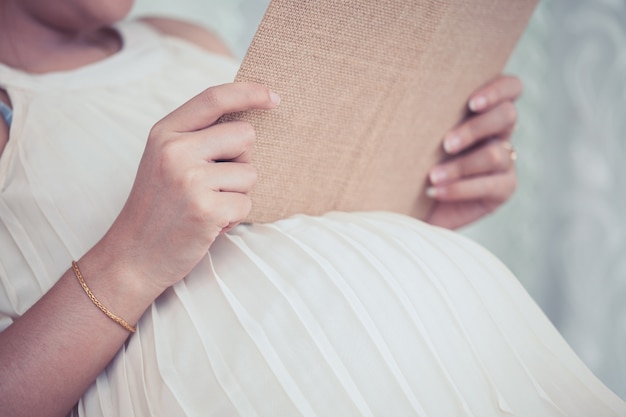 De zwangere vrouw die een boek leest treft voor geboorte en baby voorbereidingen