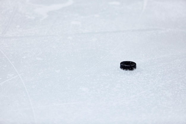 De zwarte hockey puck is op het ijs. Selectieve focus.