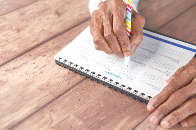 Foto concetto di scadenza con le donne anziane che segnano a mano la data sulla vista superiore del calendario calendar