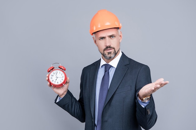 Deadline. delivery of construction object on time. businessman in protective helmet. safety business workaholic behind schedule. architect hold alarm clock. first time home buyer. getting late.