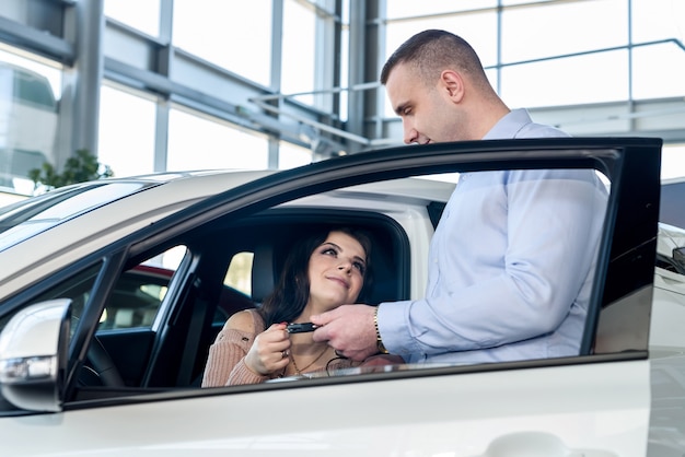 Dealer giving keys from new car to beautiful woman