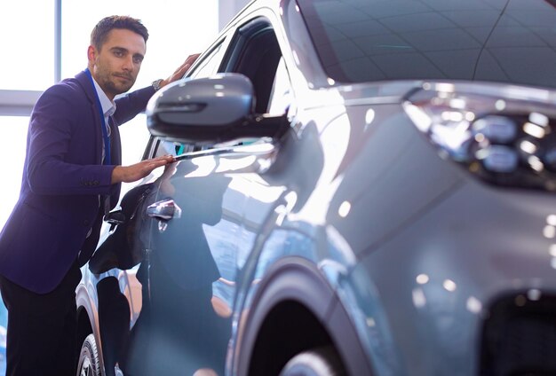 Dealer stands near a new car in the showroom