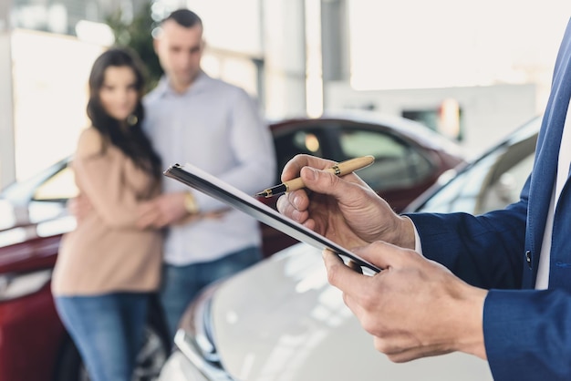 Dealerhanden met klembord en gelukkige familie erachter