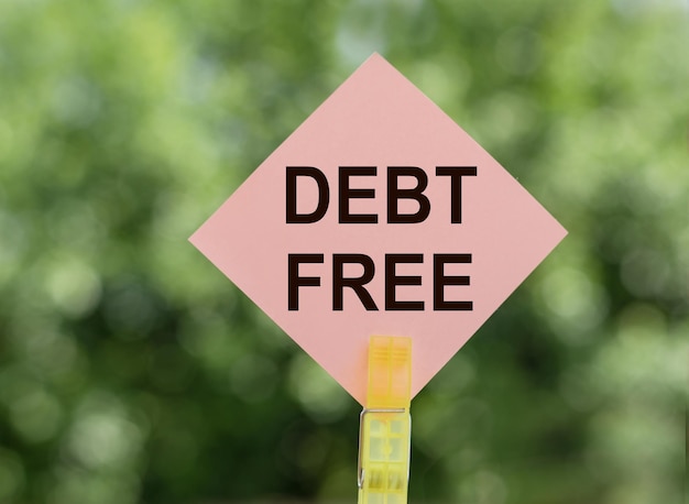 DEBT FREE текст на розовой бумаге для заметок на зеленом фоне