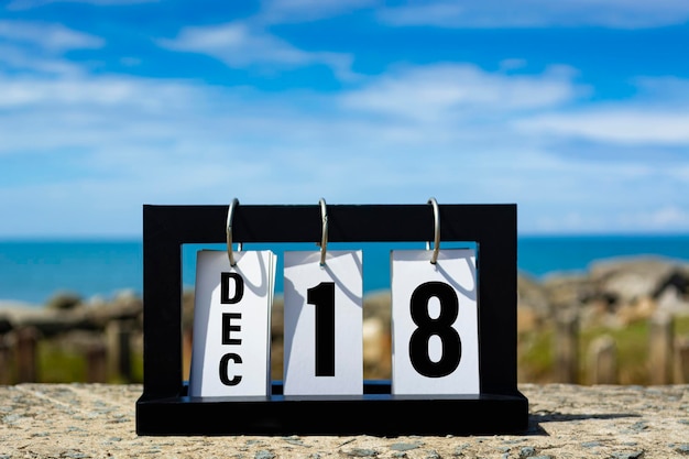 Фото 18 декабря текст календарной даты на деревянной раме с размытым фоном океана концепция календарной даты