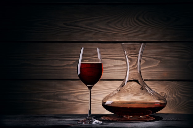 Decanter and glass with red wine on a wooden table