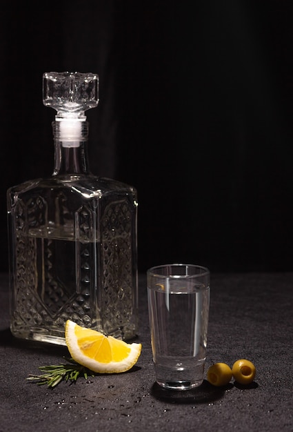 A decanter and a small glass of vodka or other colorless alcoholic beverage on a black background