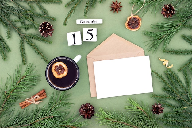 Photo december 15 calendar date white blank with craft envelope cup of tea and natural decor on green background hello winter template for your design greeting card