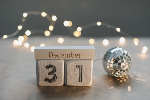 31 декабря на календаре белых кубиков на фоне светящейся гирлянды. Рождество, зима, новогодняя концепция
