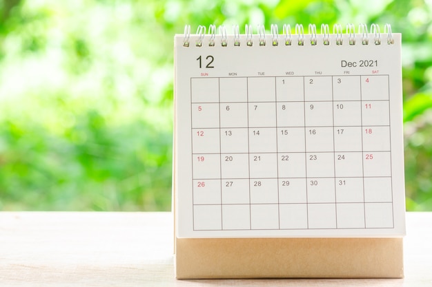 Декабрь месяц, стол календаря 2021 для организатора планирования и напоминания на деревянном столе с зеленым фоном природы.