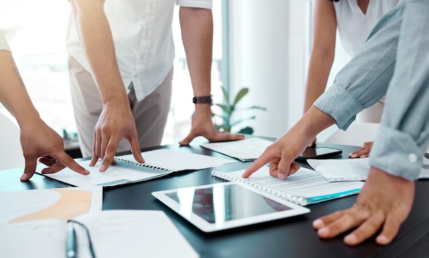 Deciding on the best way forward. Closeup shot of a group of unrecognisable businesspeople going through paperwork in an office.