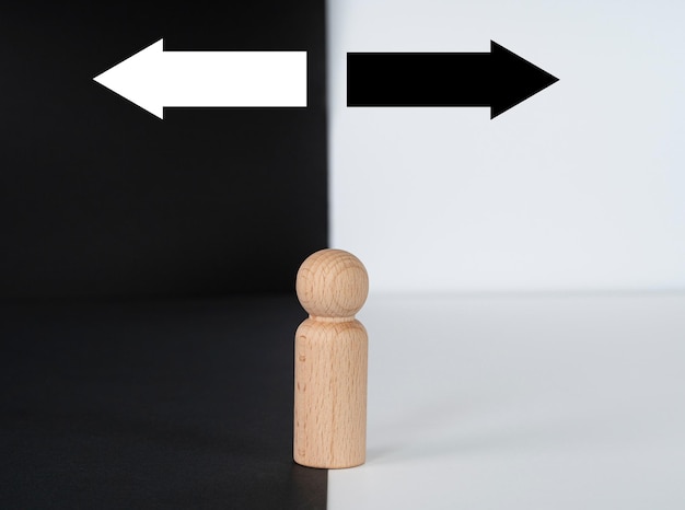 Фото Концепция принятия решений, изображаемая деревянной фигурой с двумя стрелками на черно-белом фоне