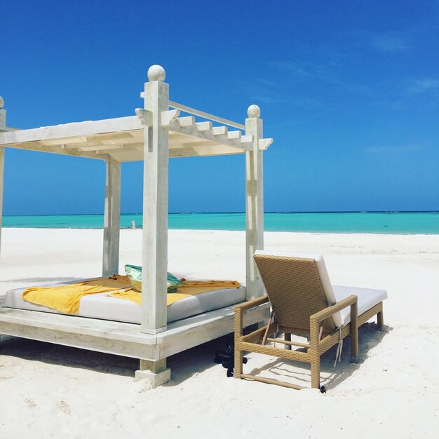 Foto deck chair accanto al letto sulla sabbia sulla spiaggia contro il cielo