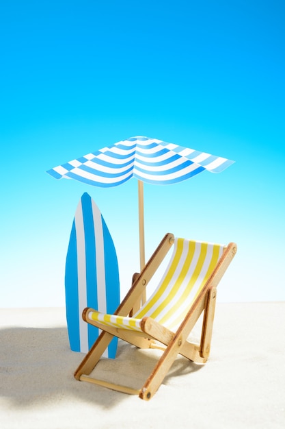 Photo deck chair under an umbrella and a surfboard on sandy beach