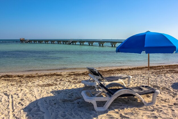 Deck chairs on beach against clear blue sky