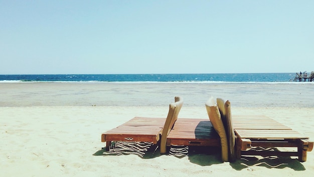 Photo deck chairs on beach against clear sky