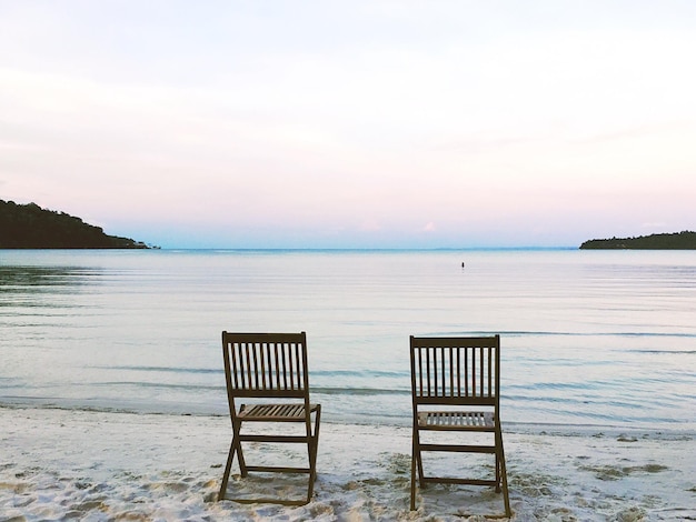 Photo deck chairs on beach against sky during sunset