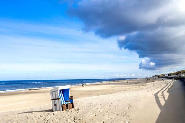 Deck chairs on beach against sky