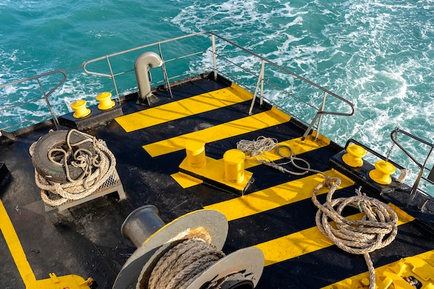 The deck of the ferry boat along with the a thick mooring rope and blue sea water wave Thailand Close up