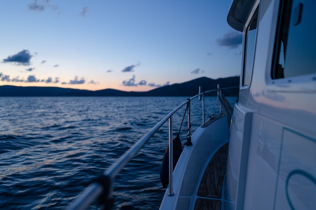 Deck of white yacht sailing in open sea at sunset