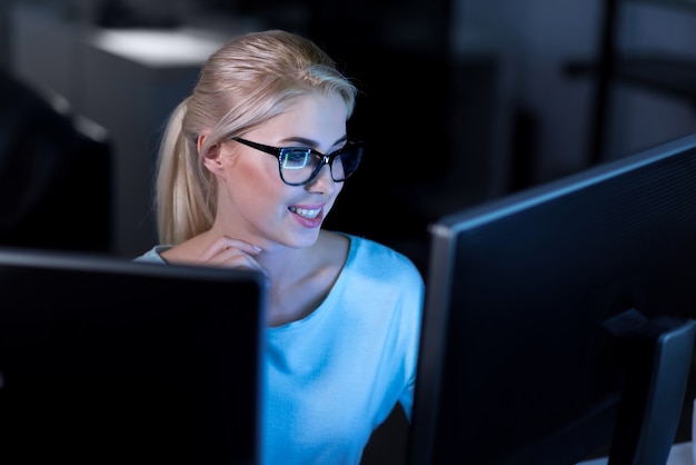 Decomposing the task. Smiling charming skilled programmer sitting in the office and using computers while working on solving password codes