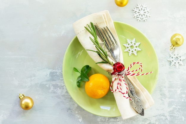 Decor tavola di natale su sfondo di pietra piatto verde posate e decorazioni vista dall'alto