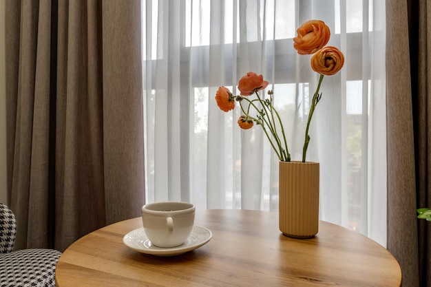 Elementi di arredo della camera degli ospiti e della stanza di riposo con un tavolino da tè, una poltrona e un mazzo di fiori e una tazza di caffè