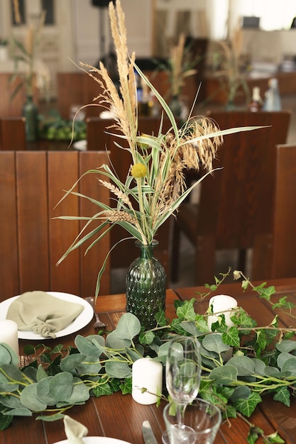 Decor voor bruiloftsbanket Houten tafelkaarsen en groene bloemen