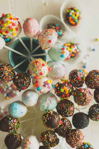 Decorated cake pops and candies on table