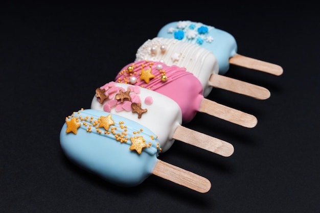 Decorated cake pops ice creams on black background